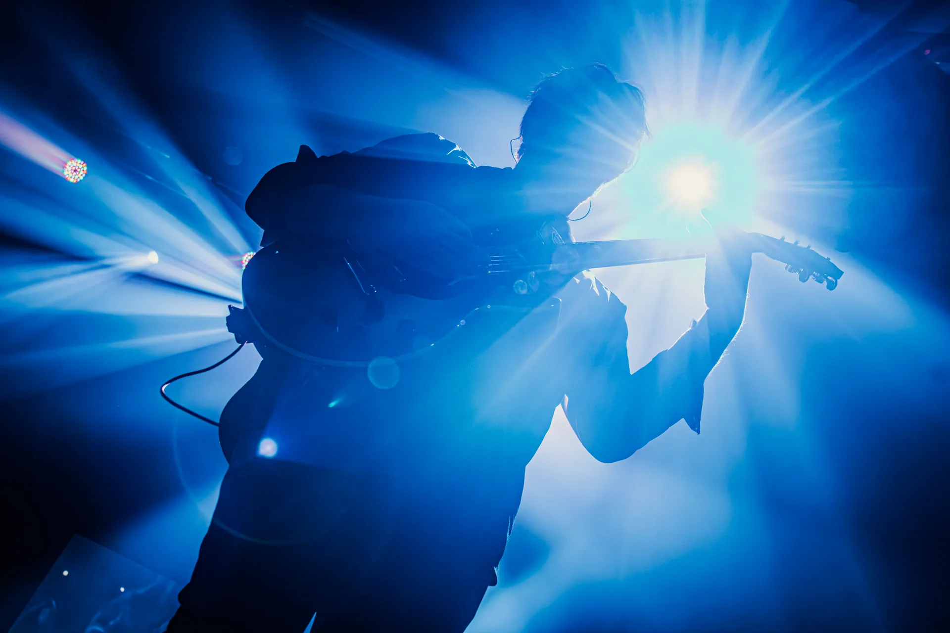 Jambi’s guitarist silhouetted against a blue spotlight
