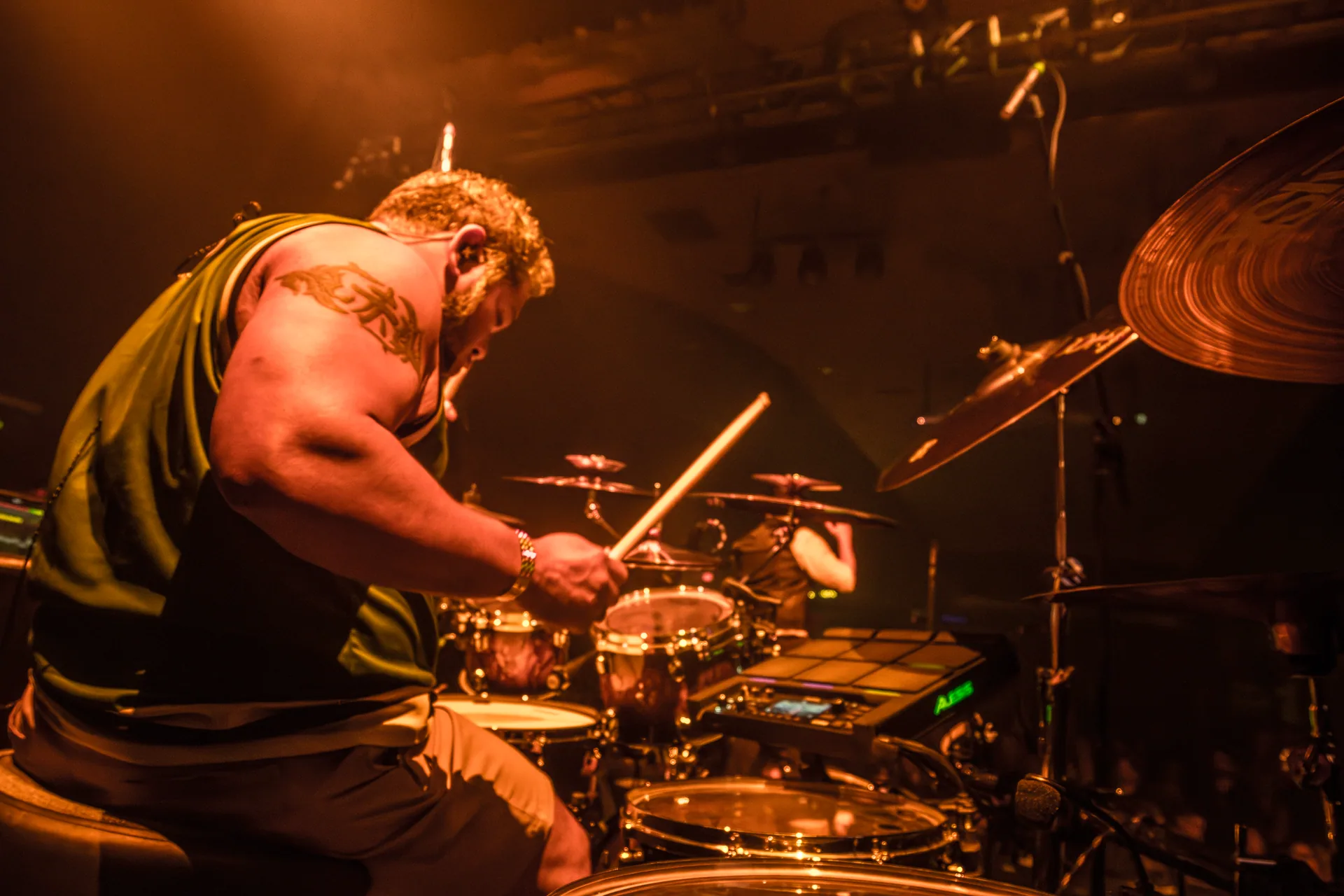 Jambi’s drummer playing under amber stage lights