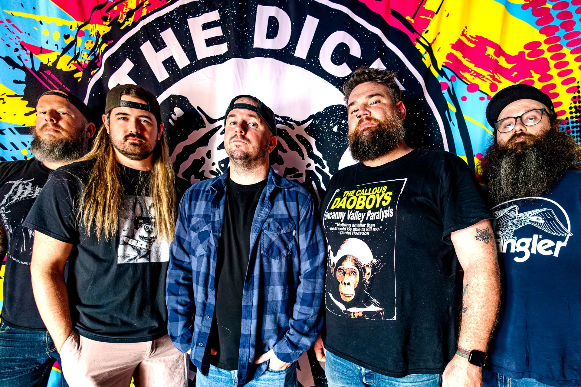 The Dick Beldings standing together in front of their colorful band banner
